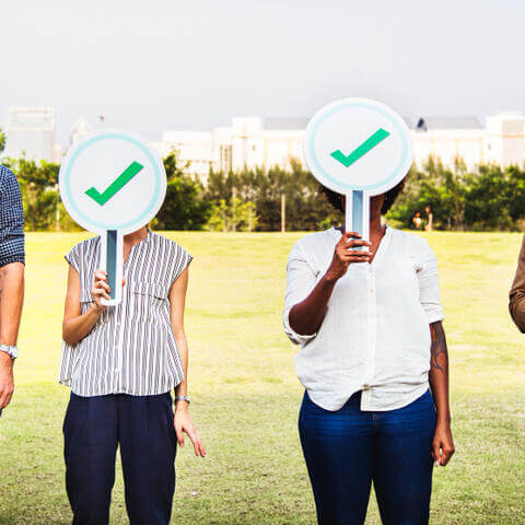 Multi-ethnic friends holding checkmark boards
